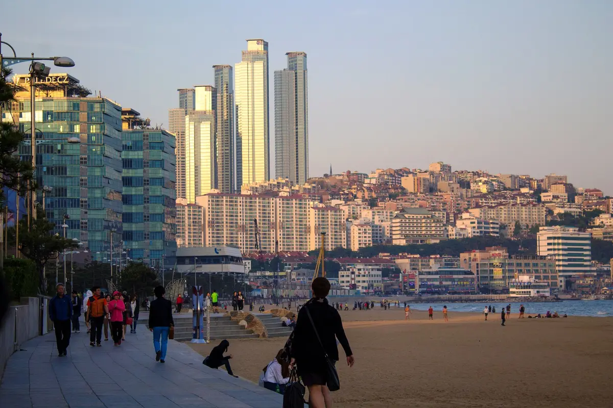 The eastern end of Haeundae Beach in evening light, with tall towers and Dalmaji Hill behind the promenade
